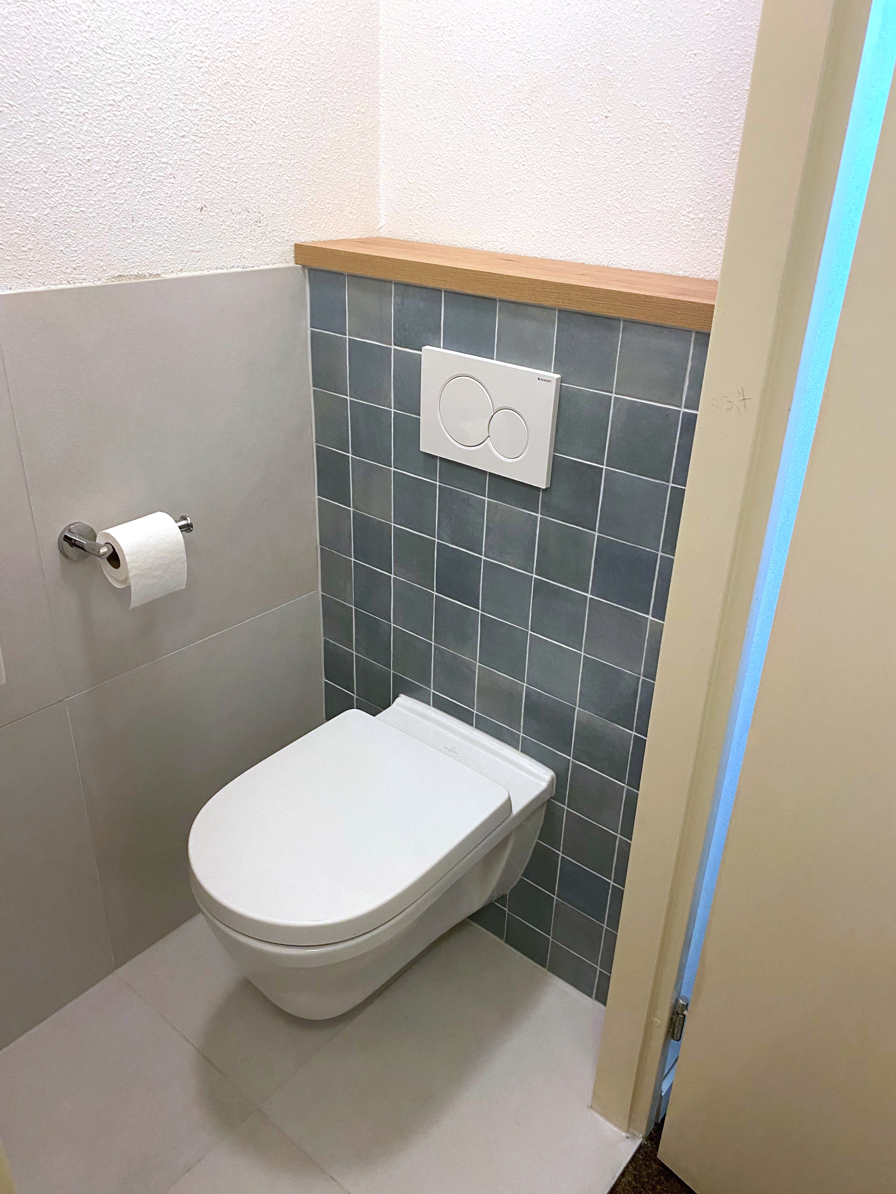 Gerenoveerd toilet met hangcloset, groene cementtegels, Geberit-bedieningsplaat en eikenhouten plankje — uitgevoerd door Smillywood